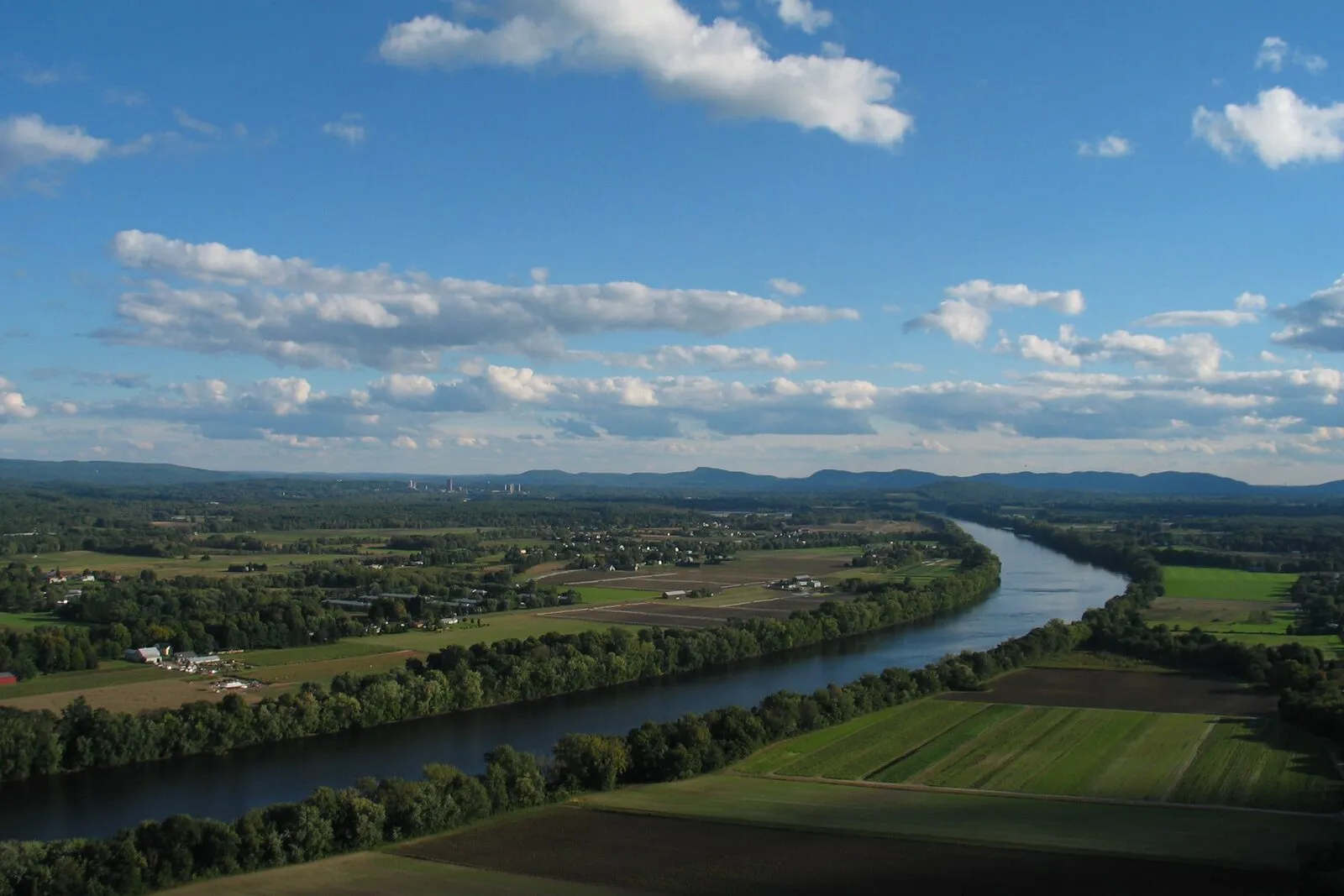 View south from the Mount Sugarloaf observation deck, with the Connecticut River winding through Pioneer Valley farmland toward the Holyoke Range on the horizon.