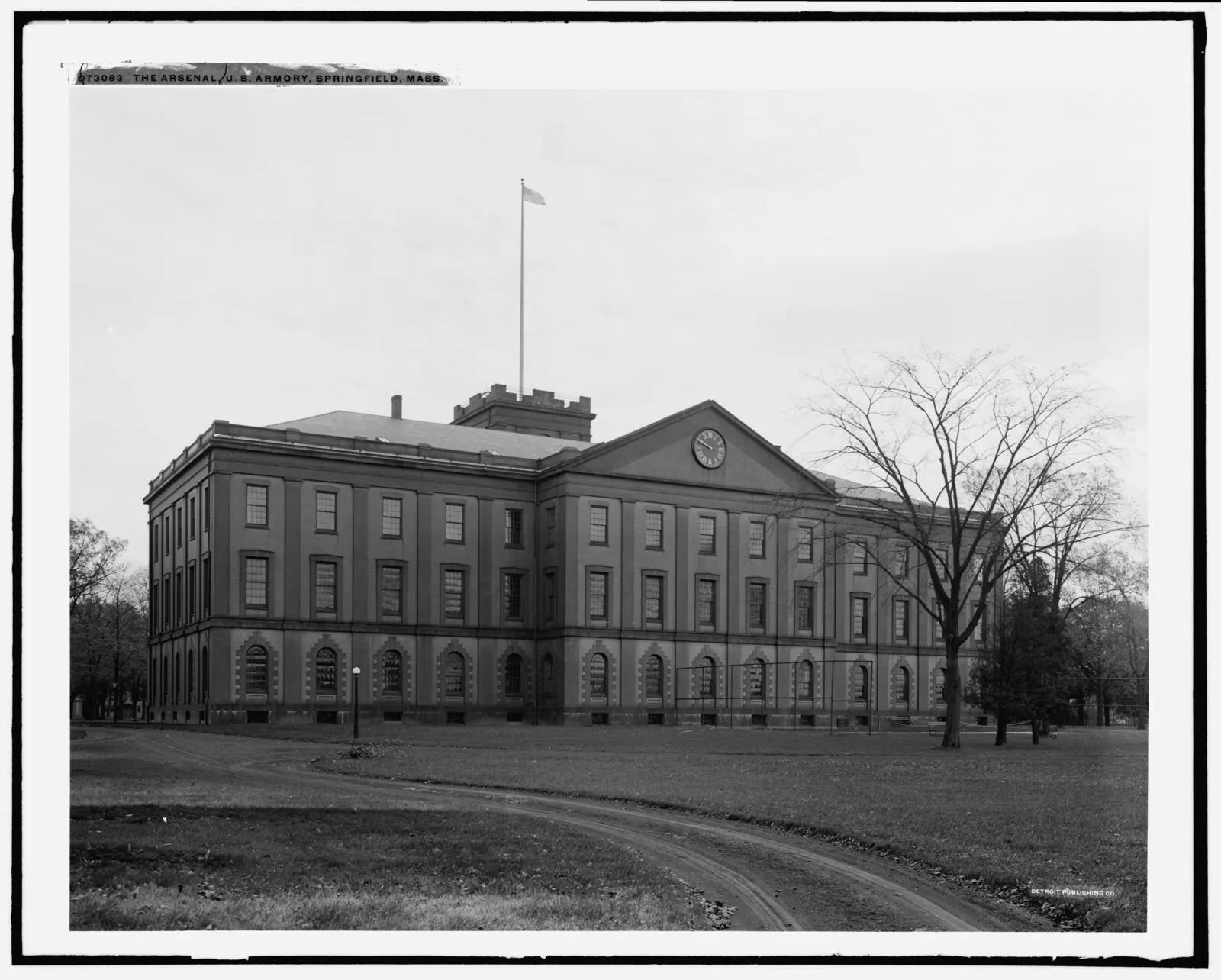 The Main Arsenal building at Springfield Armory, a broad two-story federal-style structure with a central clock tower, photographed from the parade ground.
